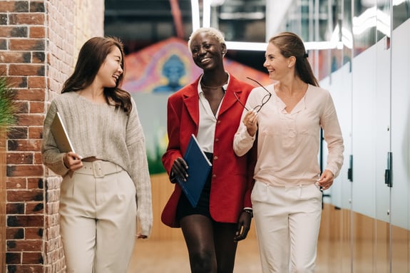 Diverse businesswomen smiling and walking together in modern workplace